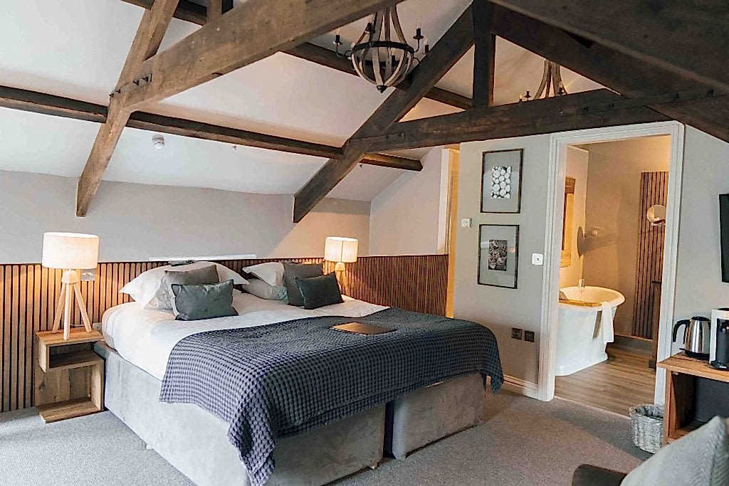 The image shows Jasper with a king size bed and exposed wooden beam features at Yorebridge House Hotel in North Yorkshire.