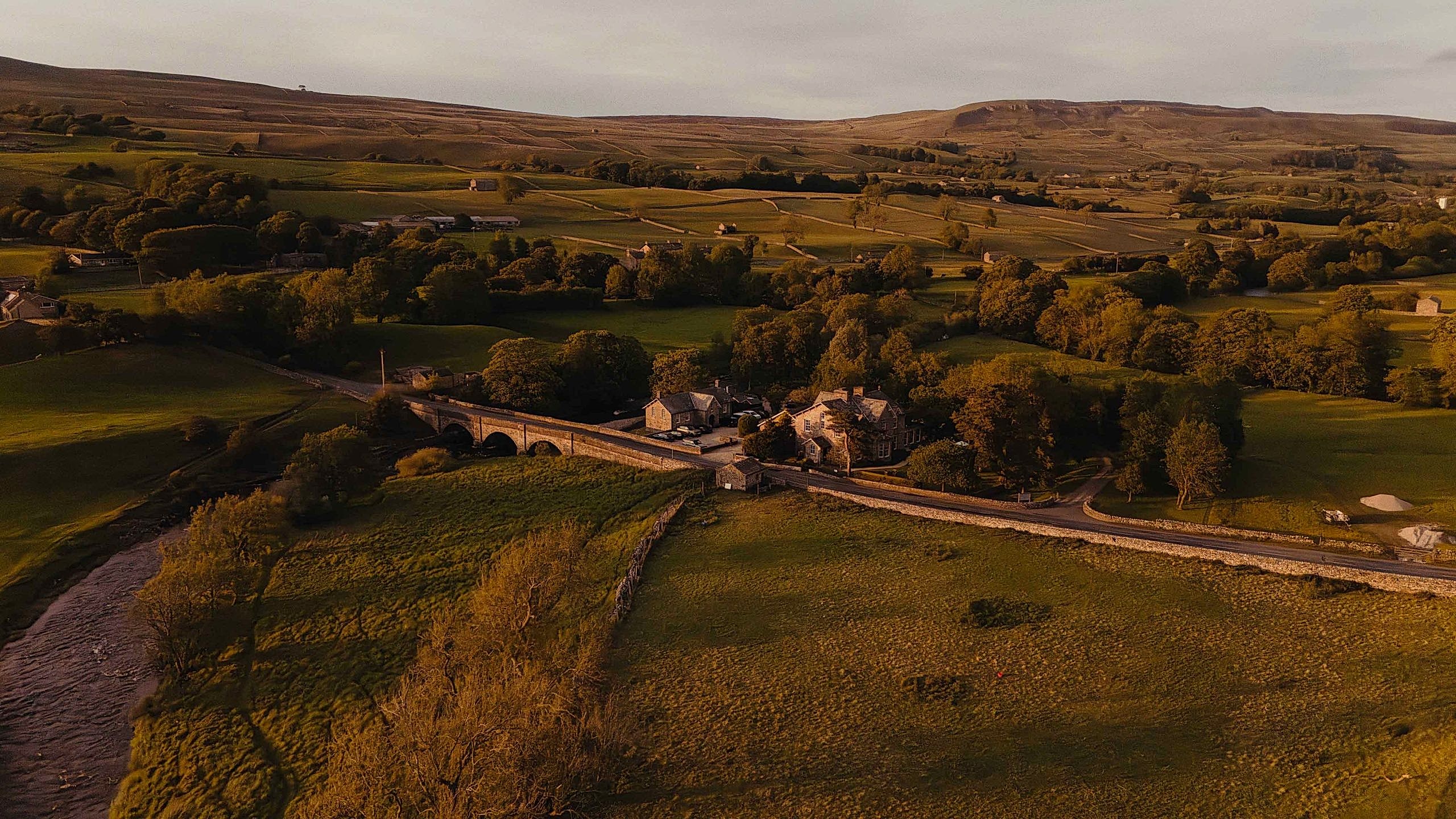The image shows a drone shot of Yorebridge House Hotel in the Yorkshire Dales countryside.