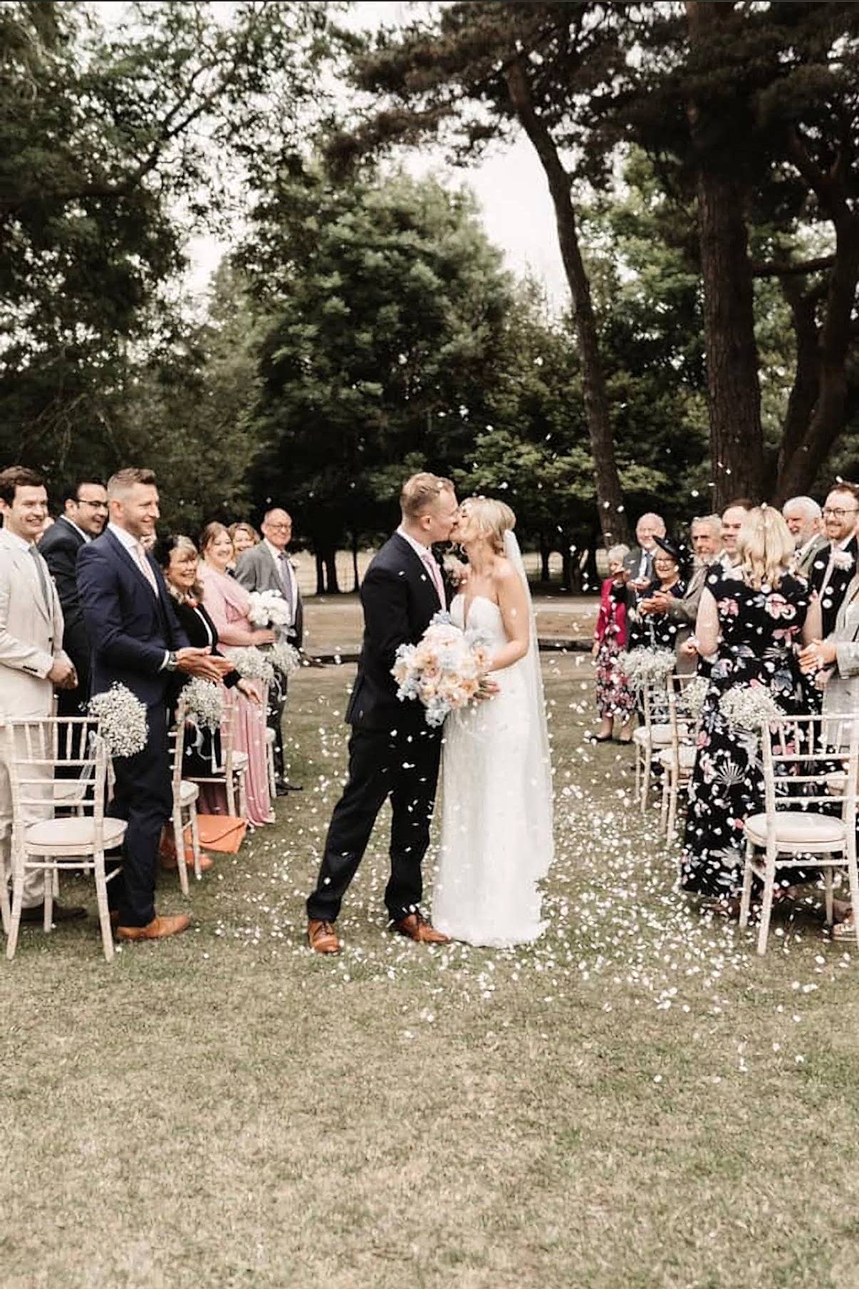 The image shows a bride and groom exchanging their first kiss as a married couple.