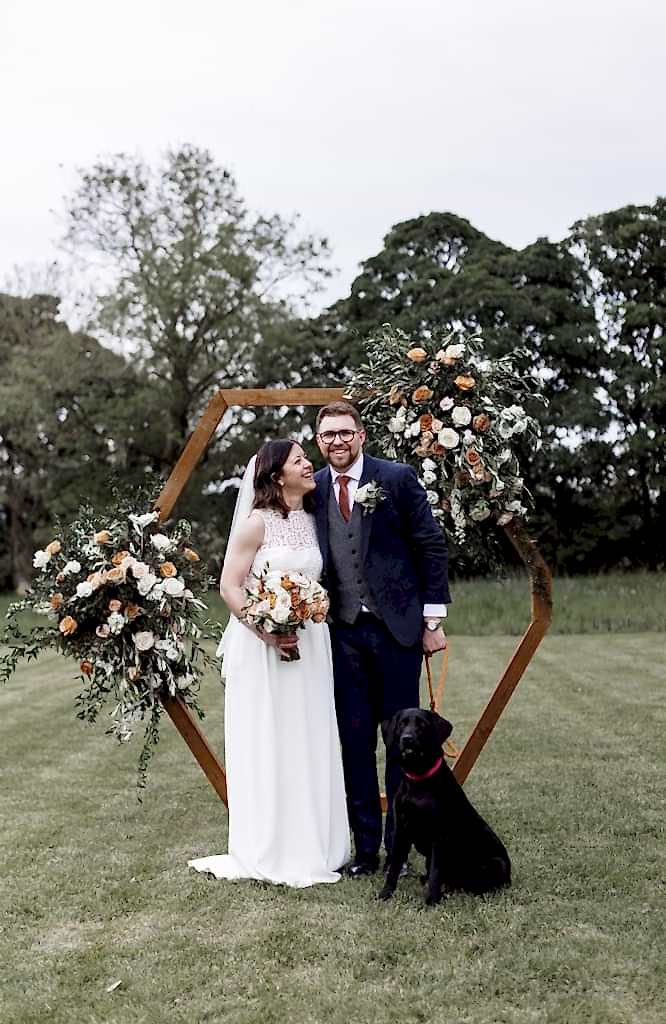 The image shows Izzie and Oli (the bride and groom) with their dog in the grounds at Yorebridge House during their wedding ceremony.