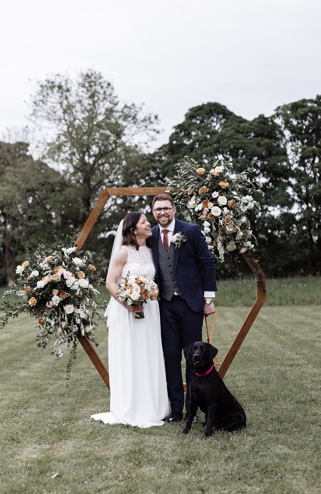 The image shows Izzie and Oli (the bride and groom) with their dog in the grounds at Yorebridge House during their wedding ceremony.